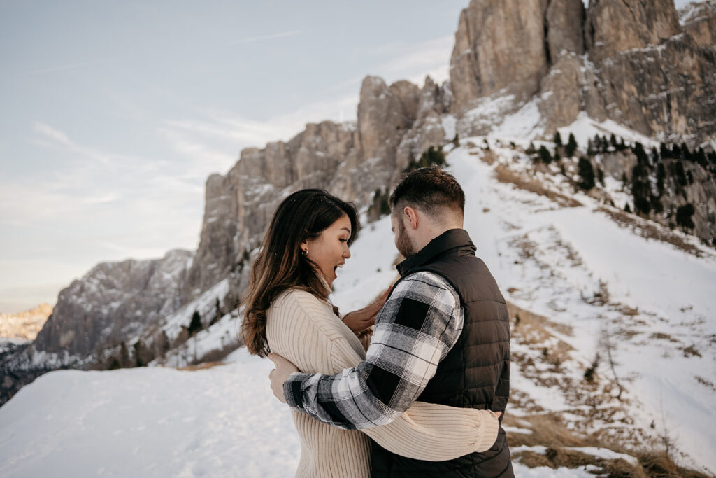 Couple embracing in snowy mountain landscape.