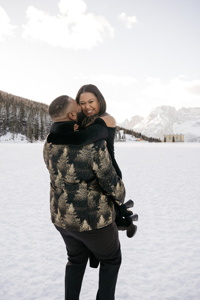 Couple embracing on snowy landscape with mountains