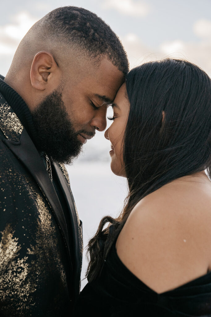 Couple embracing forehead to forehead, outdoor setting.