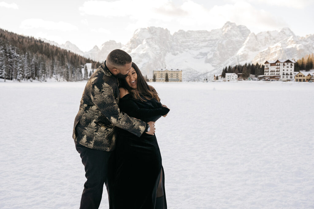 Couple laughing in snowy mountain landscape.