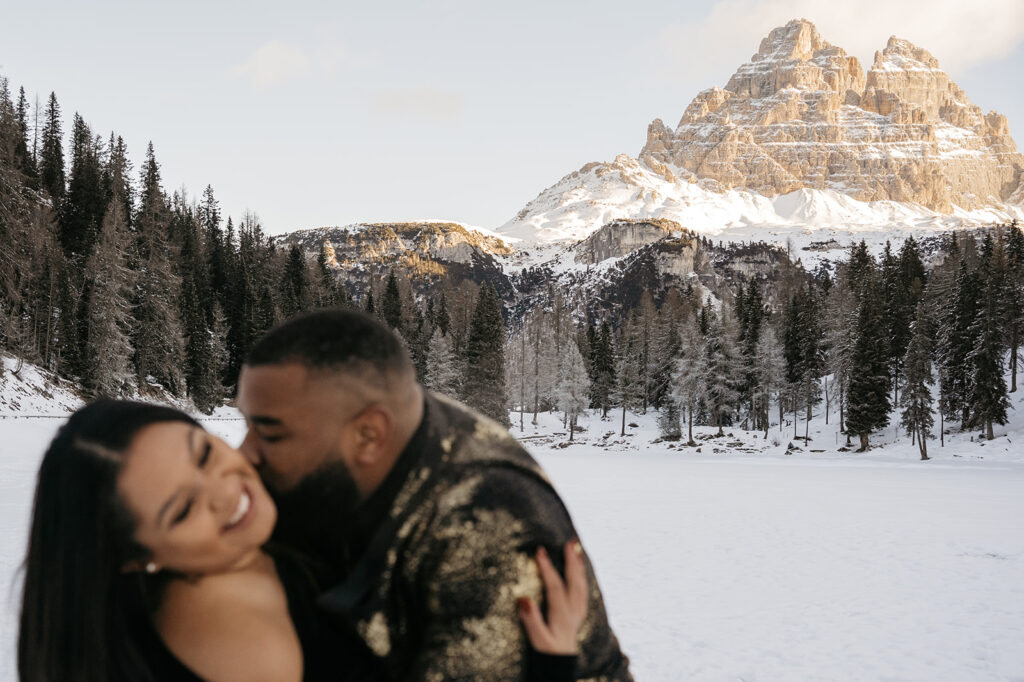Couple laughing in snowy mountain landscape.