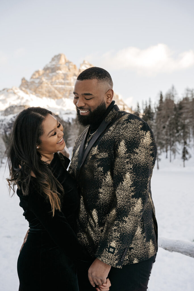 Couple smiling in snowy mountain landscape.
