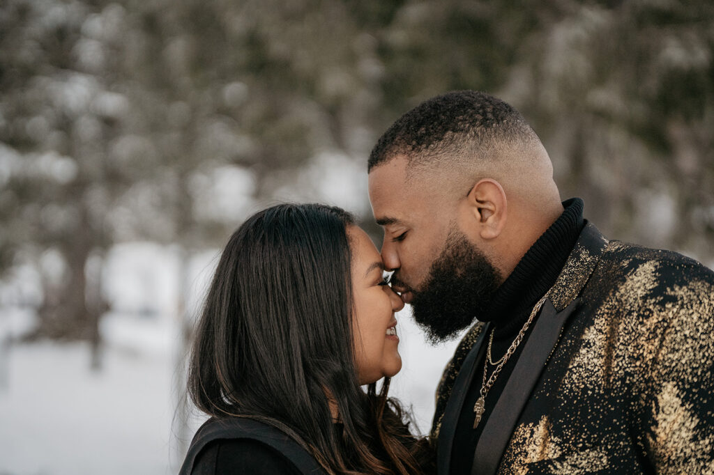 Couple smiling and embracing in snowy setting.