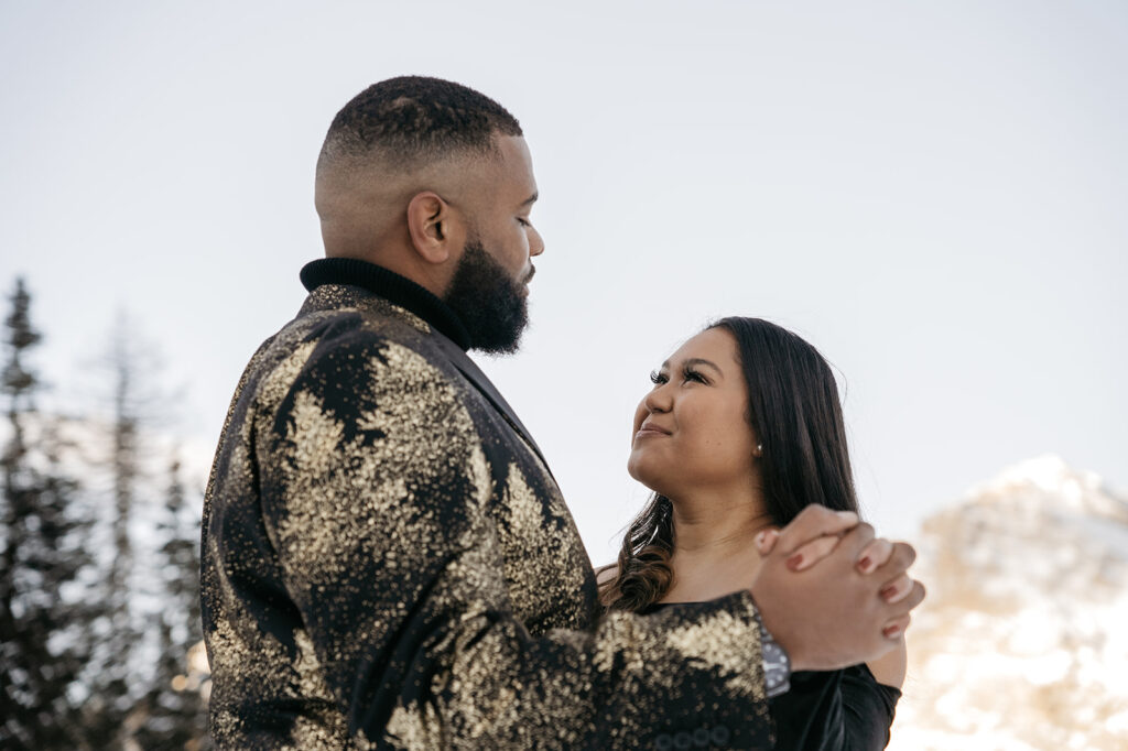Couple holding hands in snowy mountain scenery.