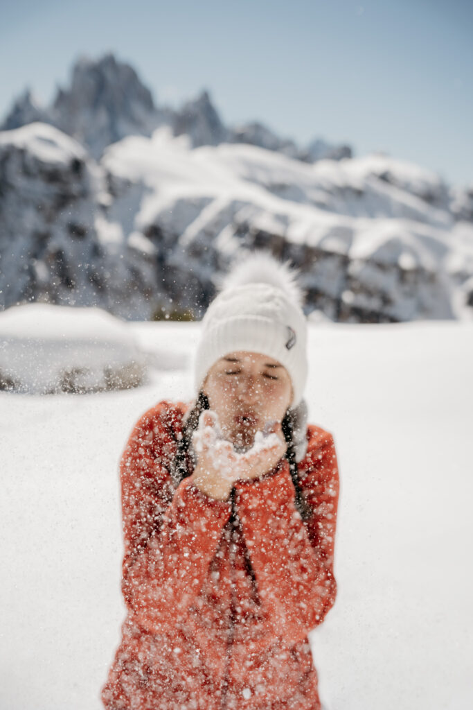 Person blowing snow in snowy mountain landscape
