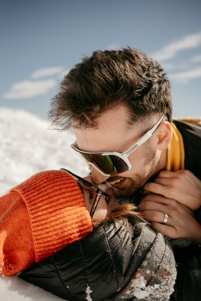 Couple laughing in the snowy outdoors.