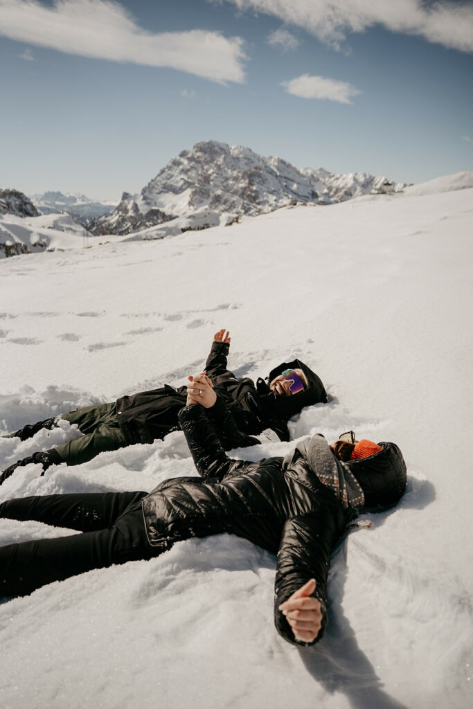 Two people lying on snowy mountain, sunny day