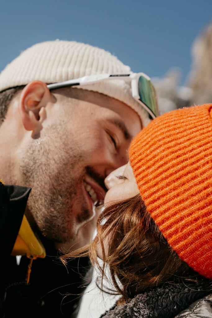 Couple kissing outdoors in winter hats.