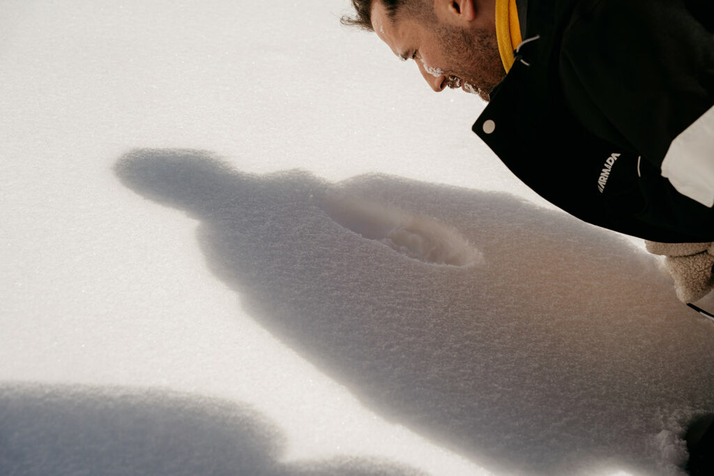 Person examining imprint in snow closely