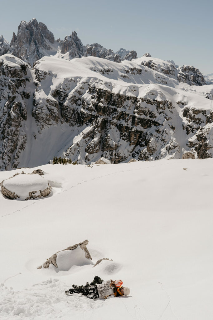 Snowy mountains with climber resting on snow.
