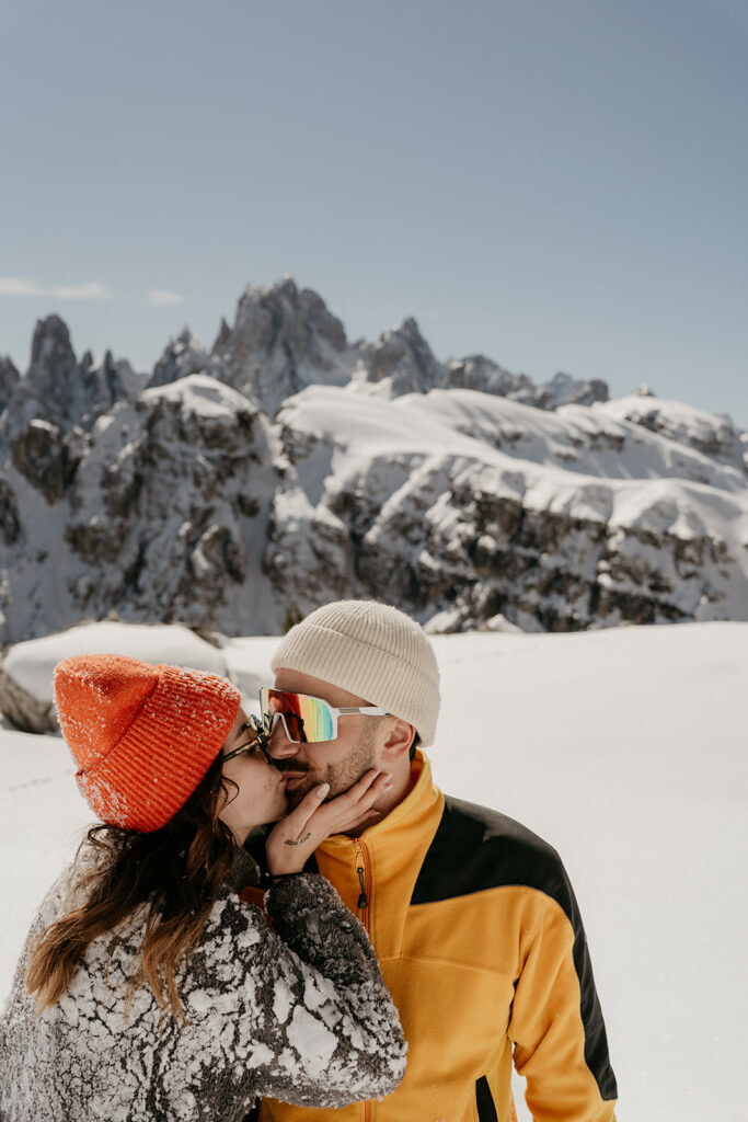 Couple kissing on snowy mountain summit.