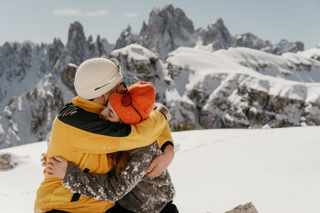 Couple hugging on snowy mountain.