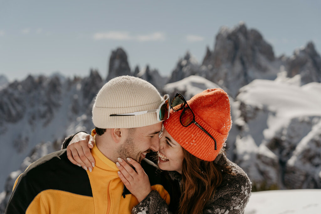 Couple smiling in snowy mountain landscape.