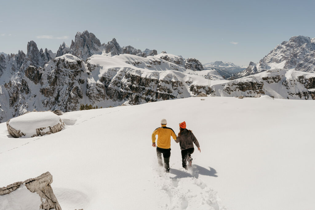 Couple hiking snowy mountains with scenic view.