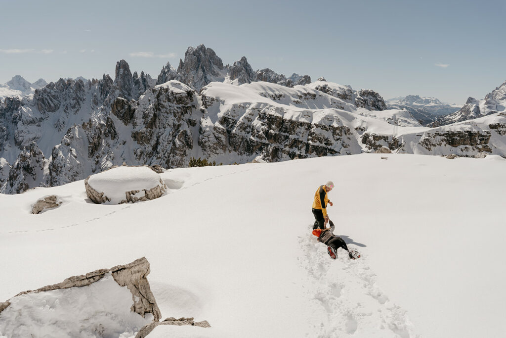 Hikers enjoying snow on mountain landscape.