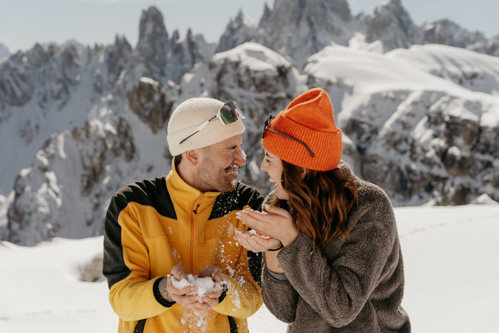 Couple laughing in snowy mountain landscape.