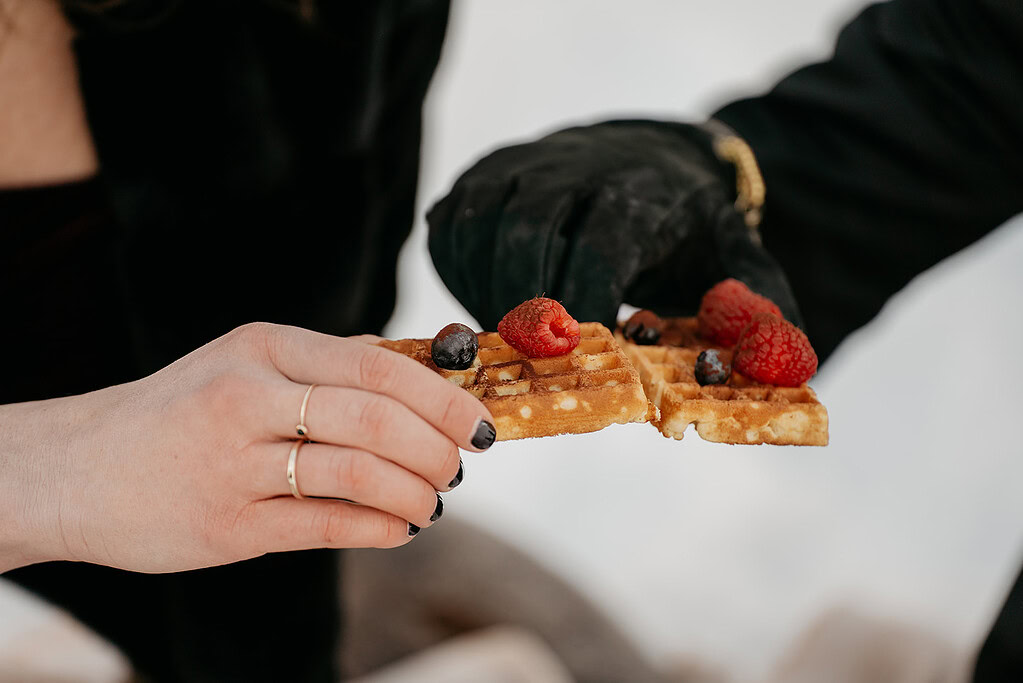 Hands holding waffles with berries