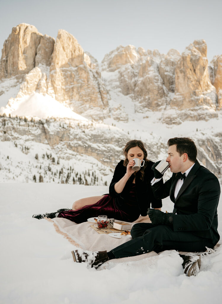 Couple enjoys picnic in snowy mountains.