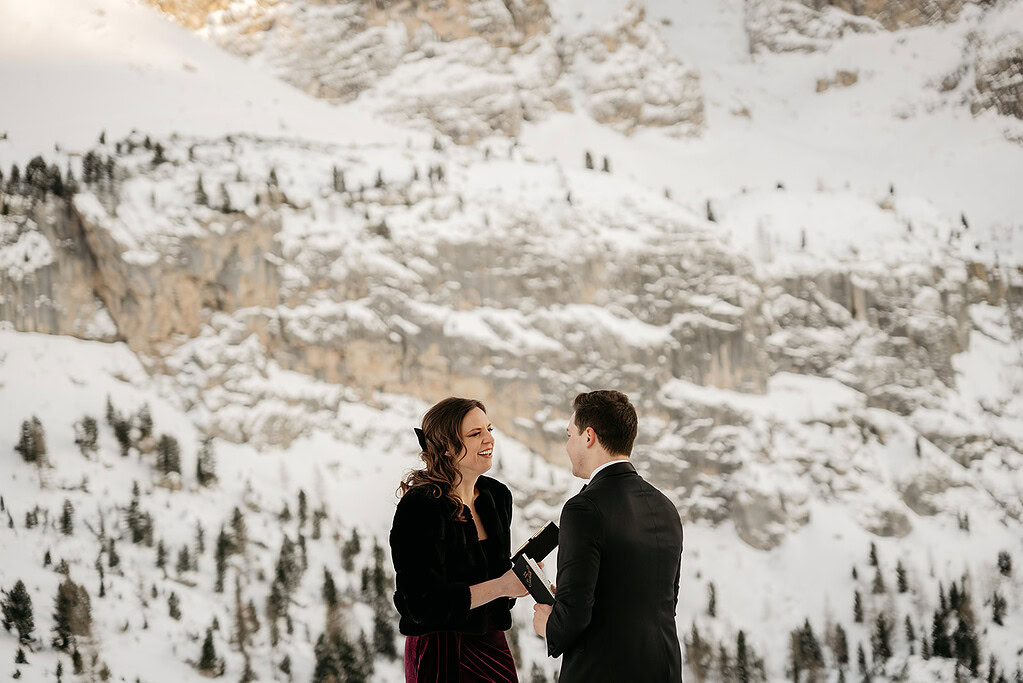 Couple exchanging vows in snowy mountain landscape.