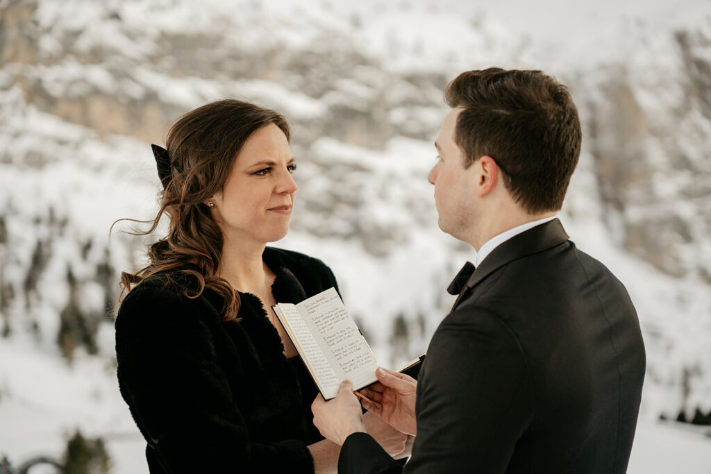 Couple exchanging vows in snowy mountain setting.