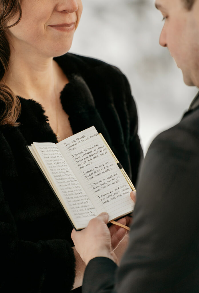 Couple exchanging vows from a notebook.