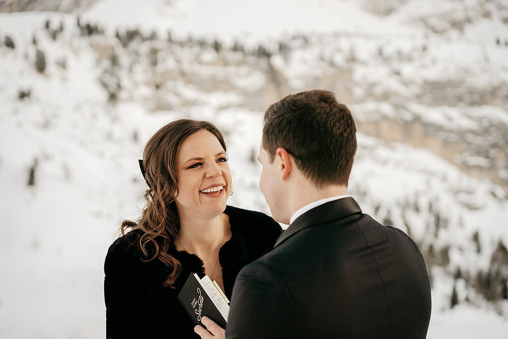 Couple exchanging vows in snowy mountain setting.