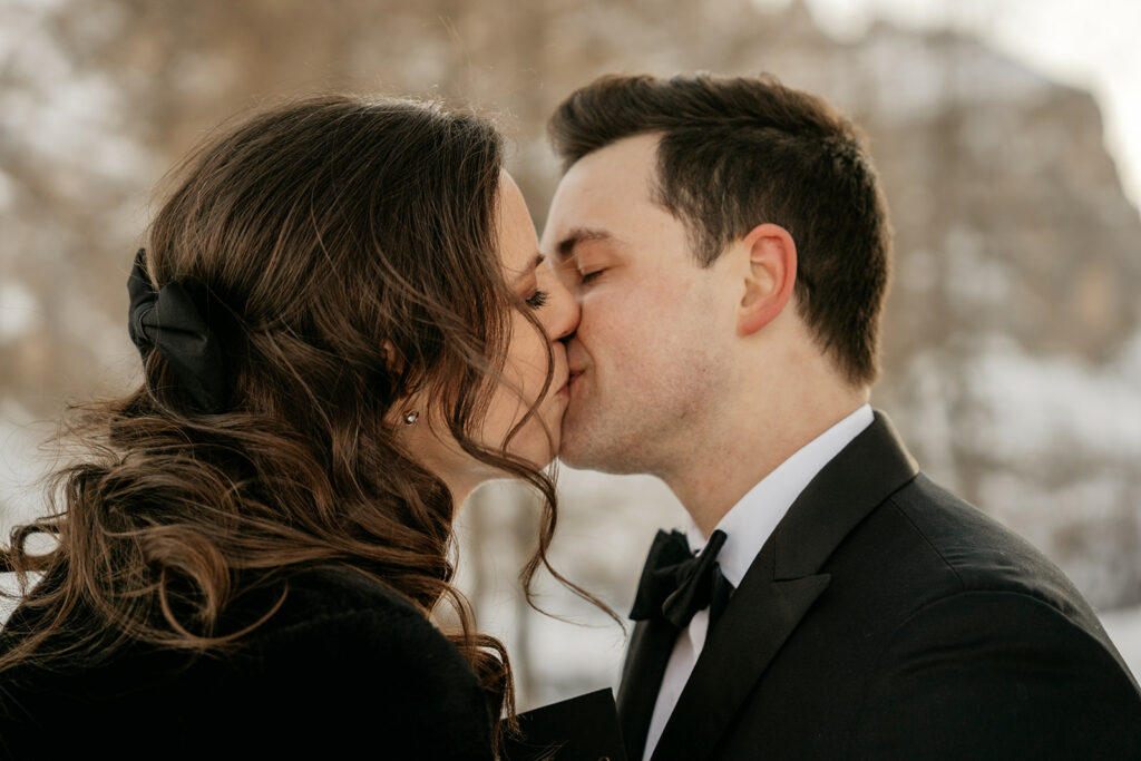 Couple kissing outdoors in winter setting.