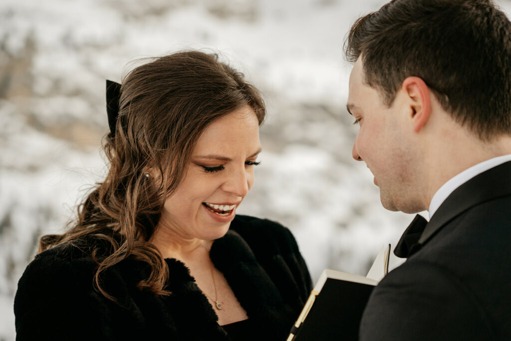 Couple smiling with a book in snowy setting.