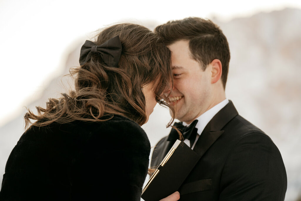 Couple smiling, sharing a tender moment outdoors.