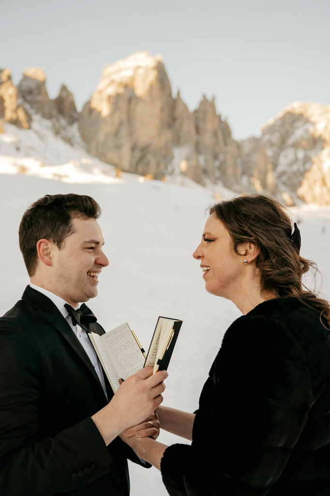 Couple exchanging vows in snowy mountain landscape.