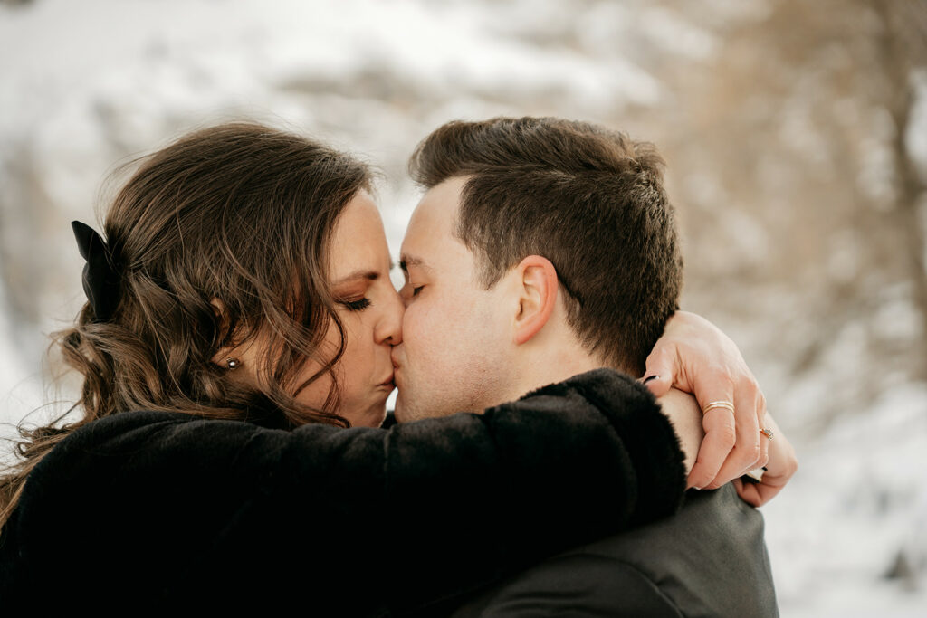 Couple kissing in snowy landscape.