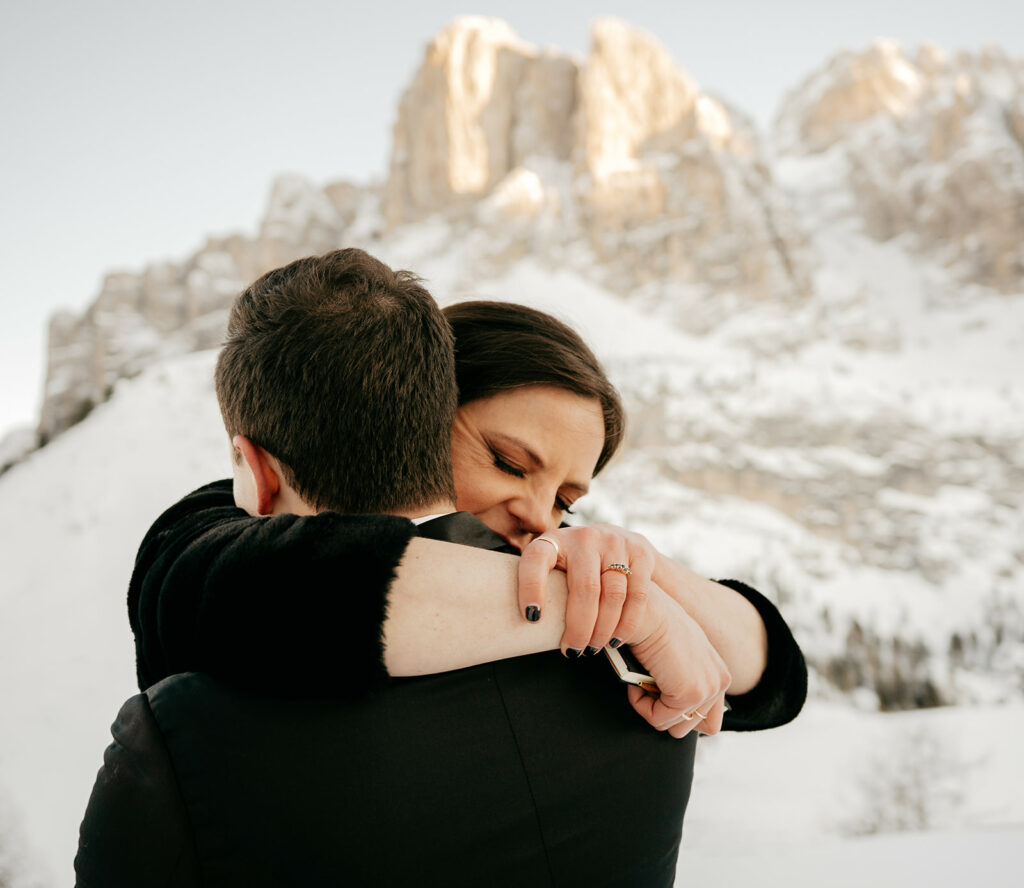Couple embracing in snowy mountain landscape.