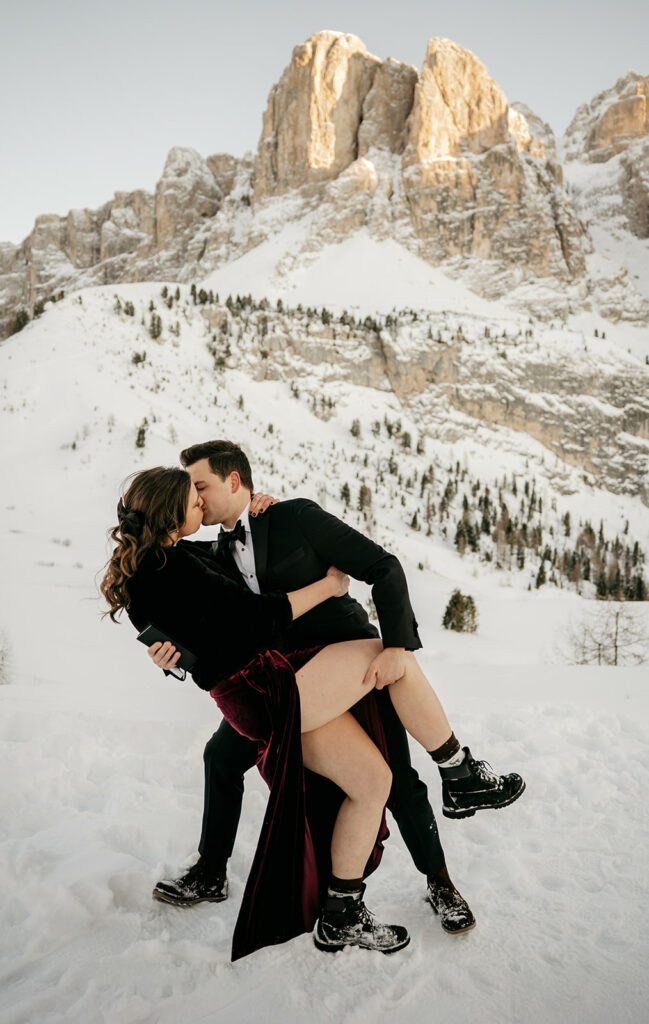 Couple kissing in snowy mountain landscape.
