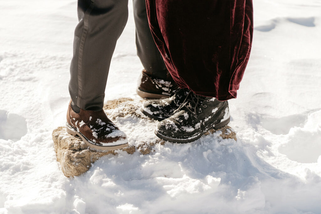 Couple in snowy boots on rock, winter scene.