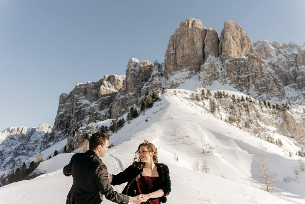 Couple dancing on snowy mountain landscape.