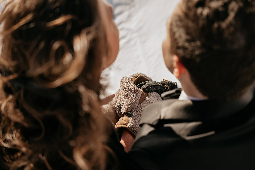 Couple holds falcon on gloved hand, close-up view.