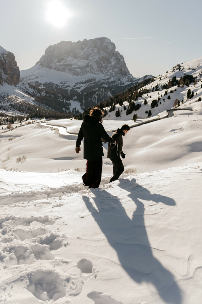 Two people walking in snowy mountain landscape.