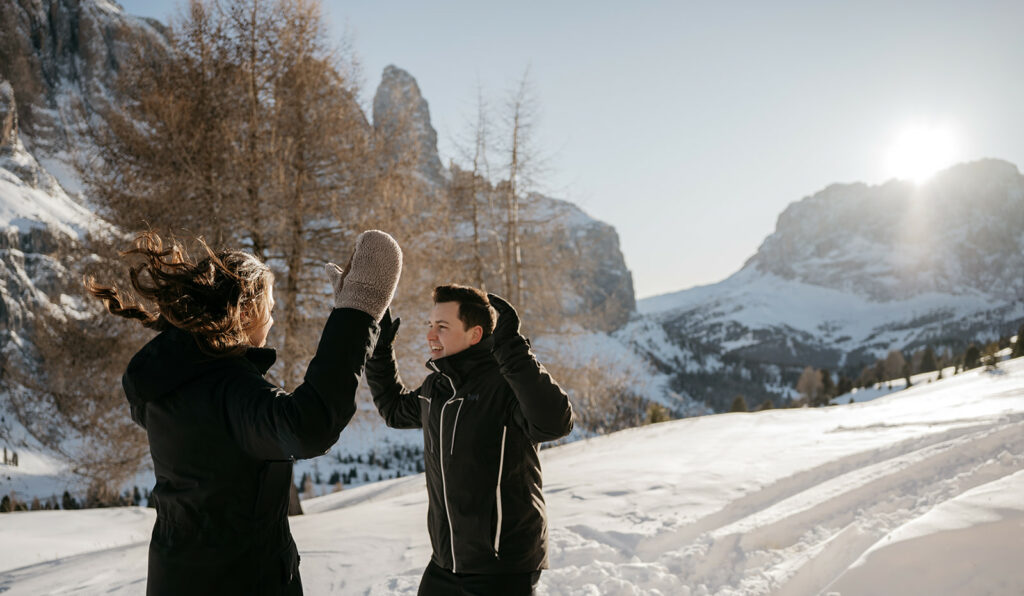 People playing in snowy mountain landscape at sunrise.