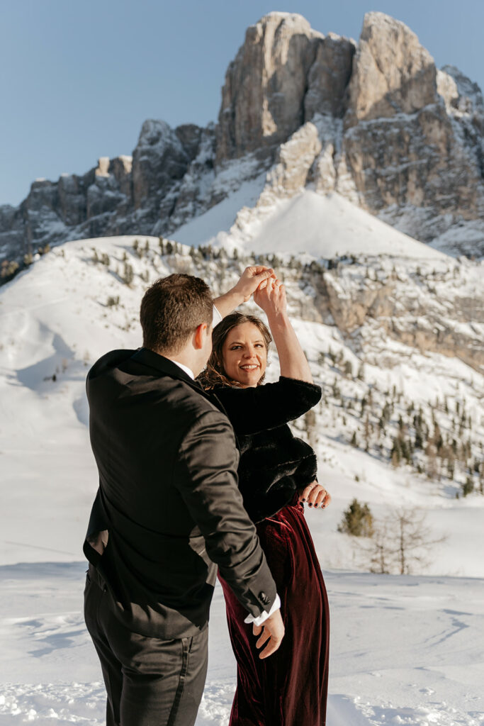 Couple dancing in snowy mountain landscape.