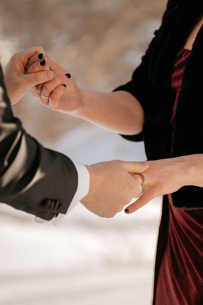 Exchanging rings during wedding ceremony outdoors.