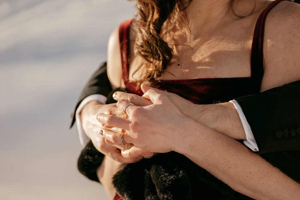 Couple embracing, showing hands and elegant dress.
