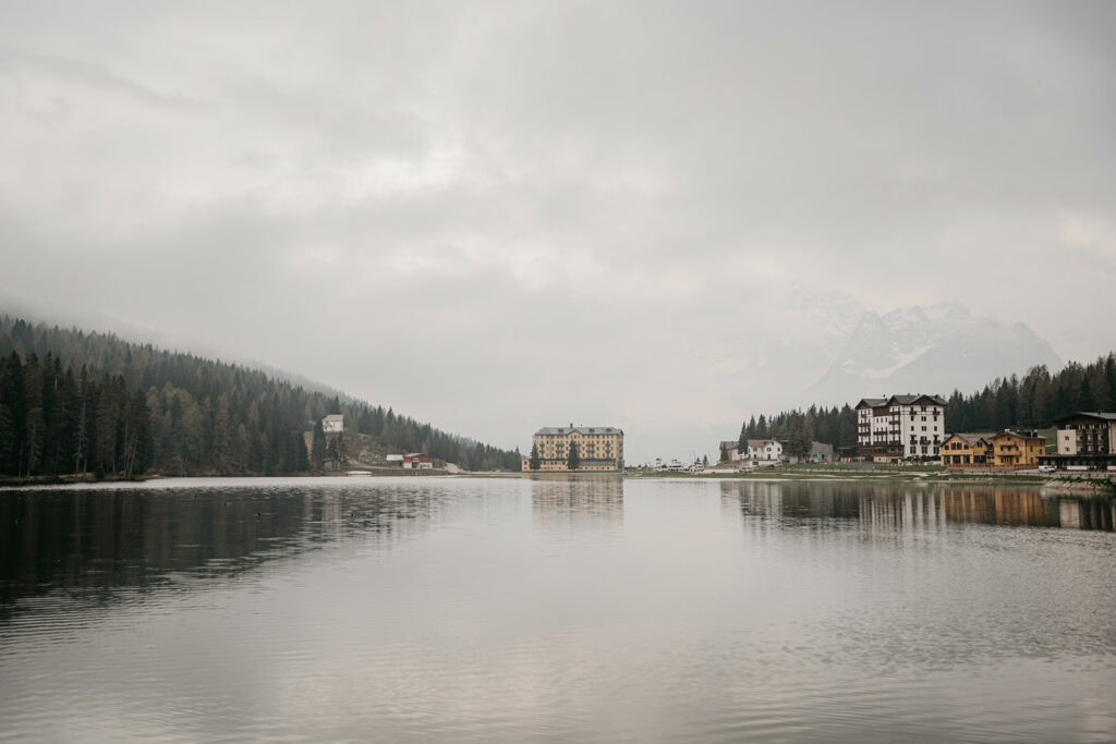 Lakeside buildings surrounded by misty mountains and forest.