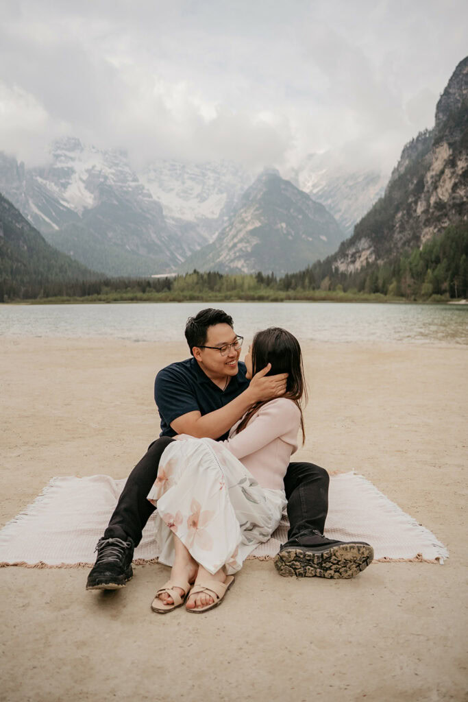 Couple sitting by lake with mountain backdrop