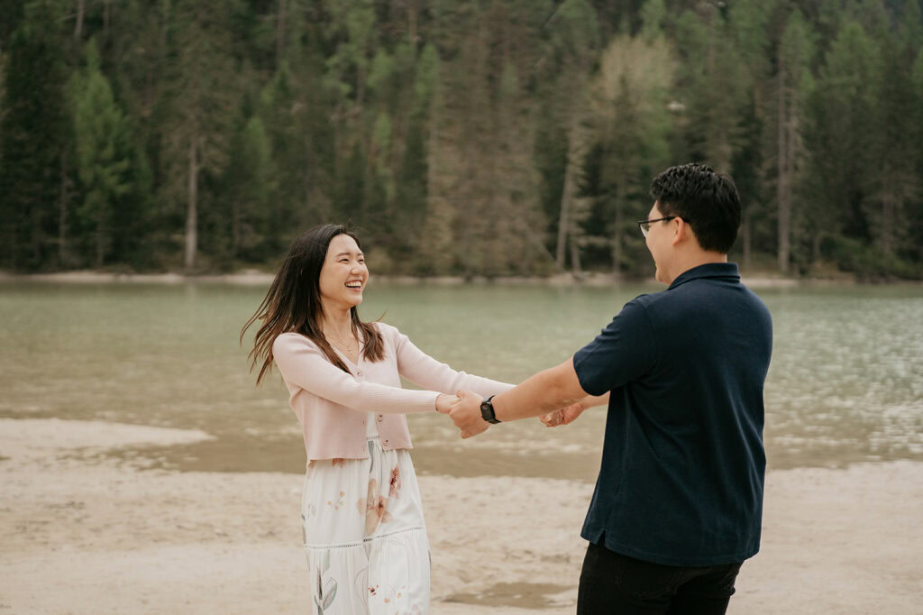 Couple holding hands by the lake, smiling.