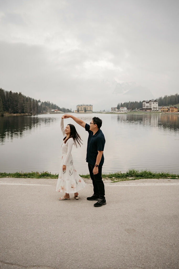 Couple dancing by a serene lakeside view.