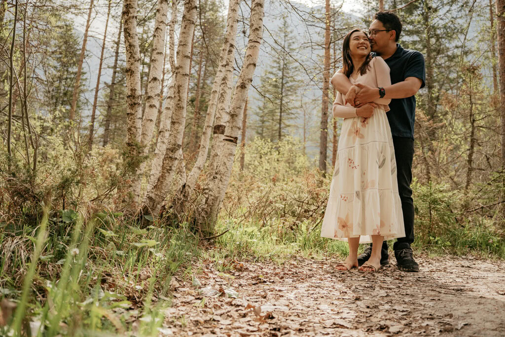 Couple embraces in forest on a sunny day.