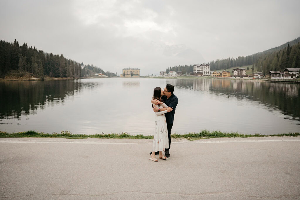 Couple kissing by a scenic lakeside.