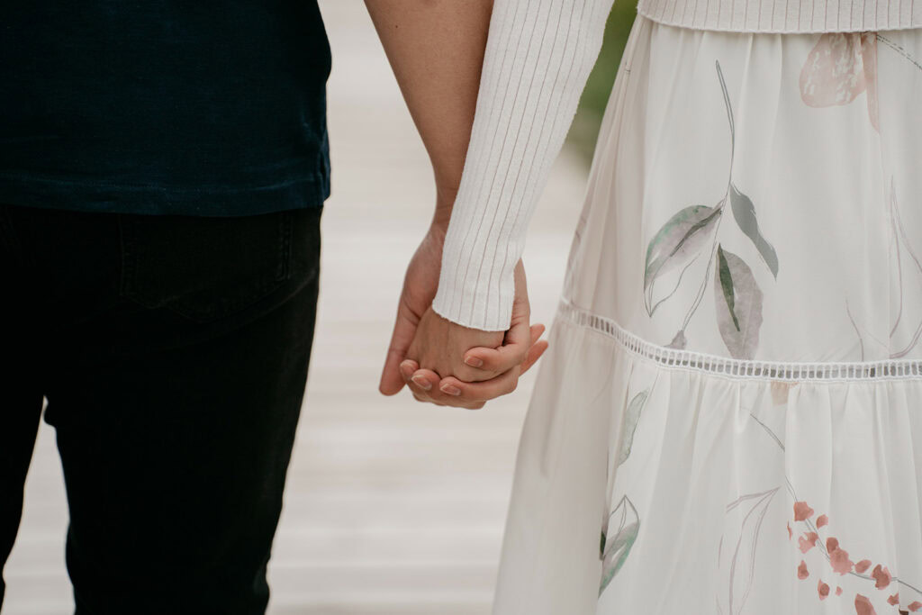 Couple holding hands, wearing floral and dark clothing.