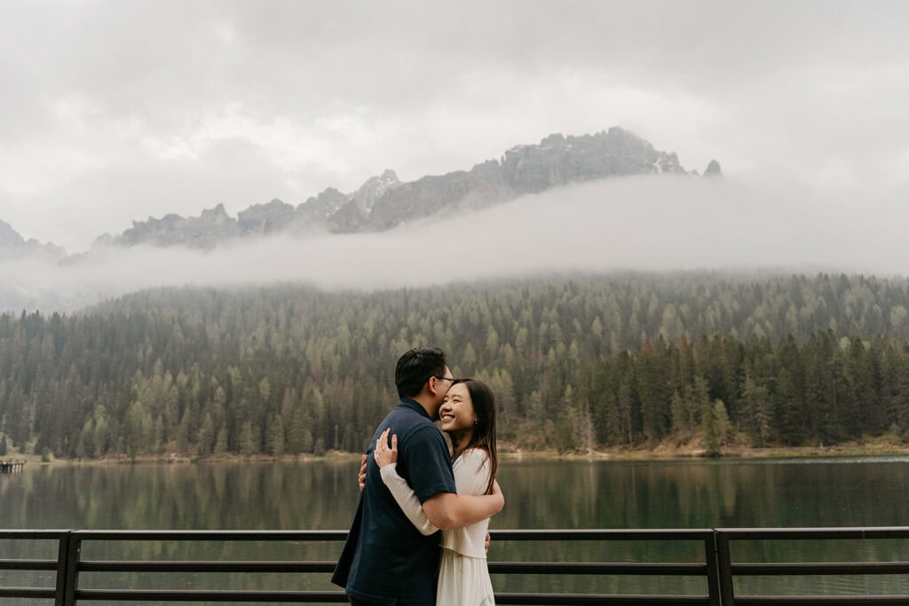 Couple embraces by misty mountain lake view.