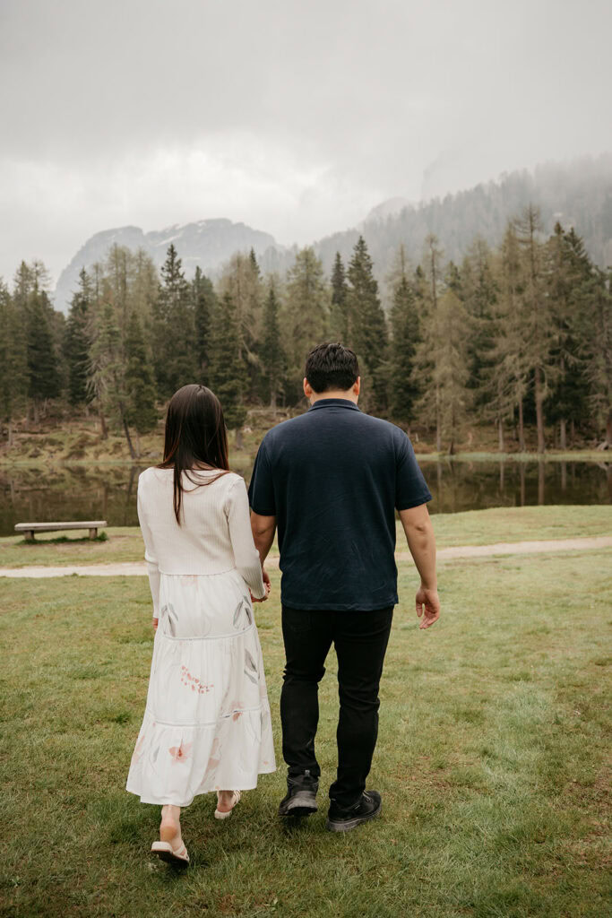 Couple walking near a forested lake landscape.